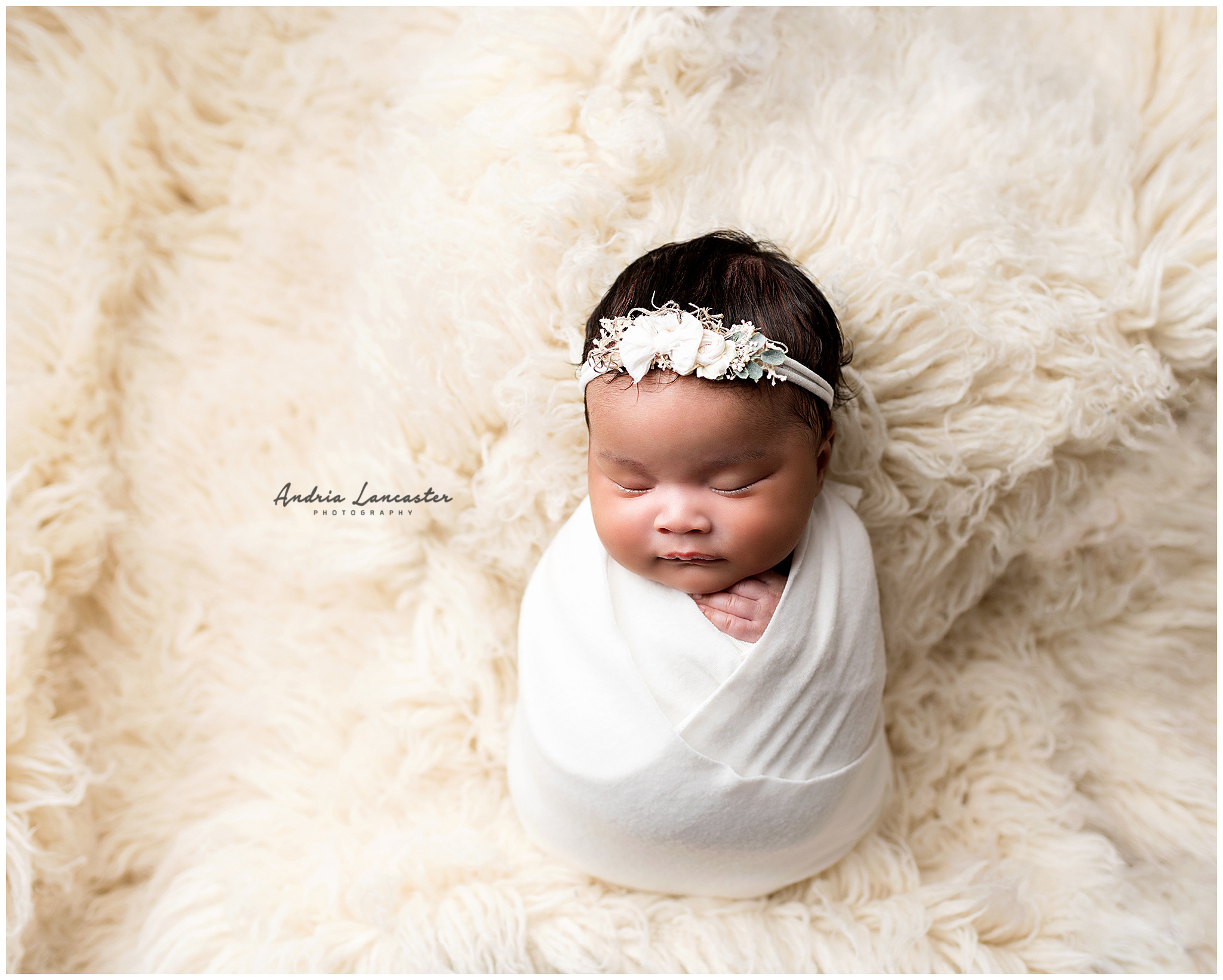 Newborn photography session white wrapped girl on flokati