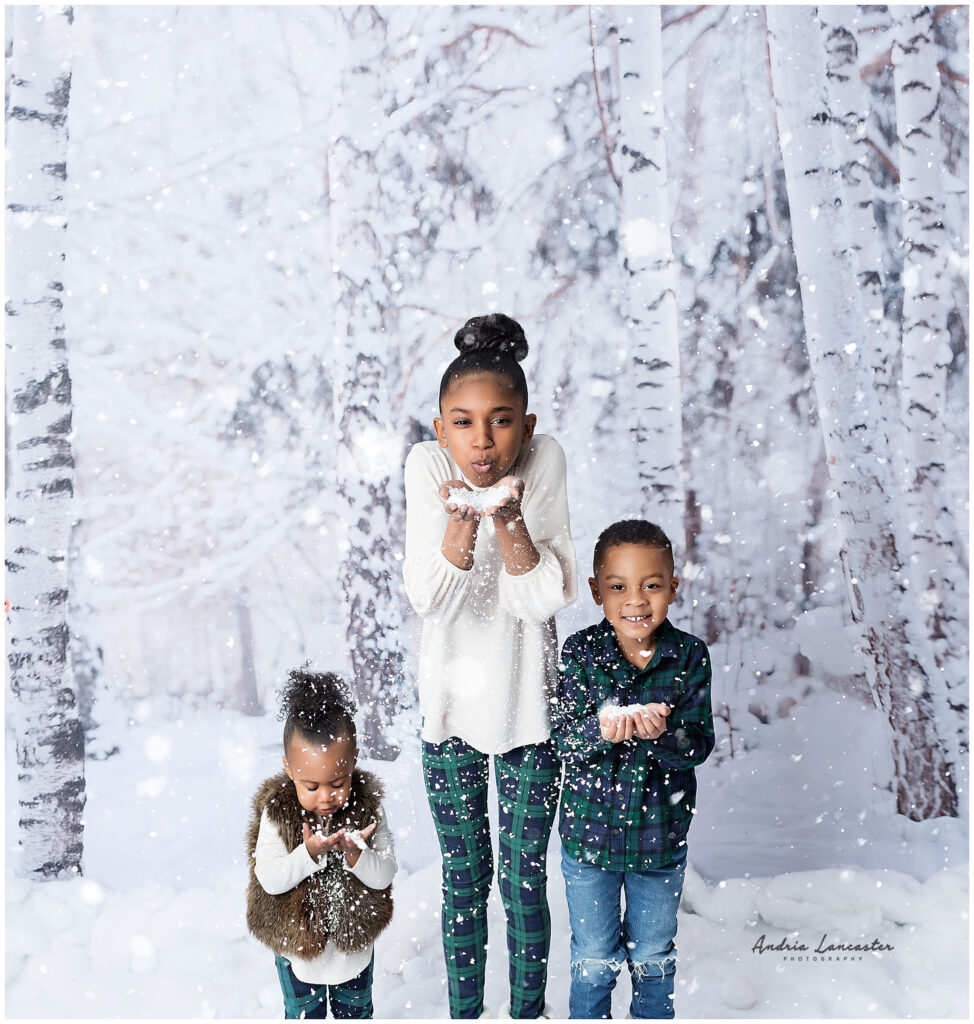 Children blowing faux snow at camera