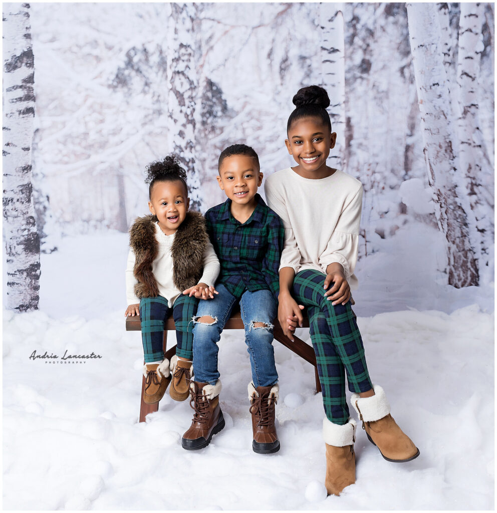 three children sitting on bench is faux snow