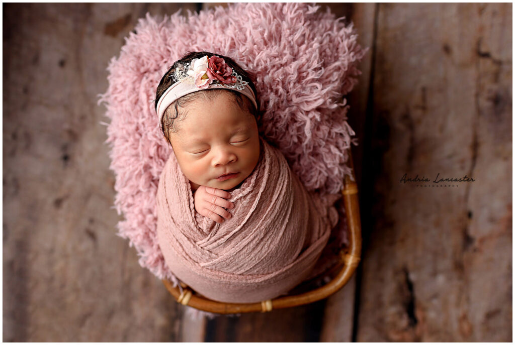 newborn wrapped and posed in rattan basket pink set