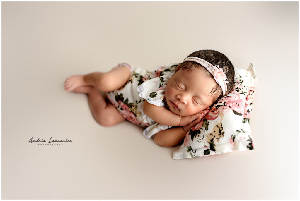 newborn in side laying pose on pillow pink floral 