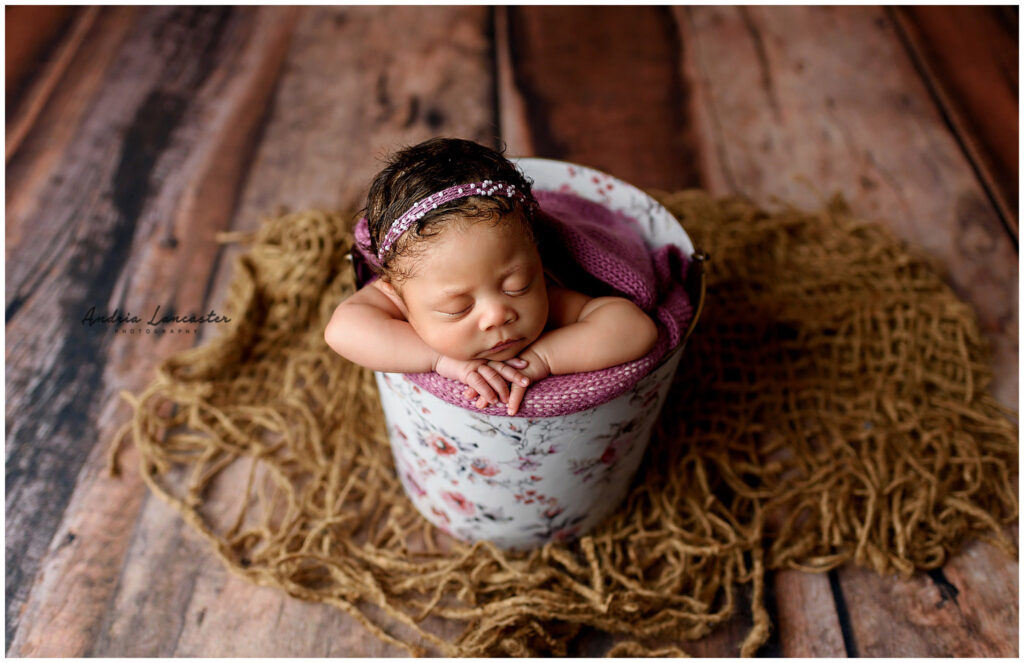 newborn in floral bucket and pink wrap