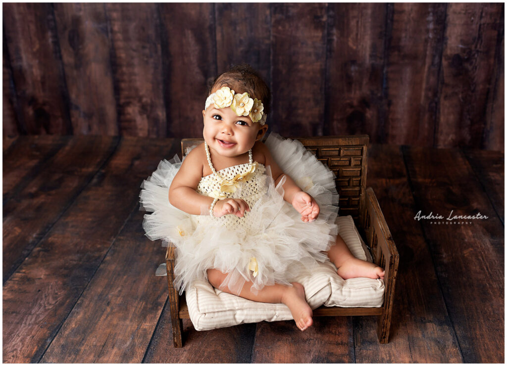 6 month old in studio sitting on bench smiling