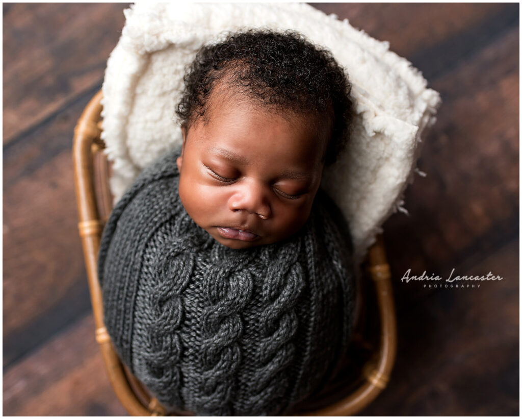 newborn boy wrapped in gray knit wrap