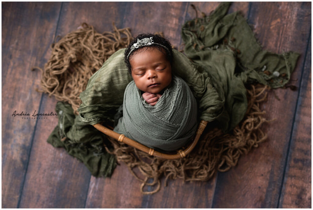 newborn posed in basket with green wrap 