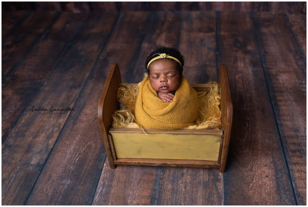 newborn wrapped in bed prop mustard colors