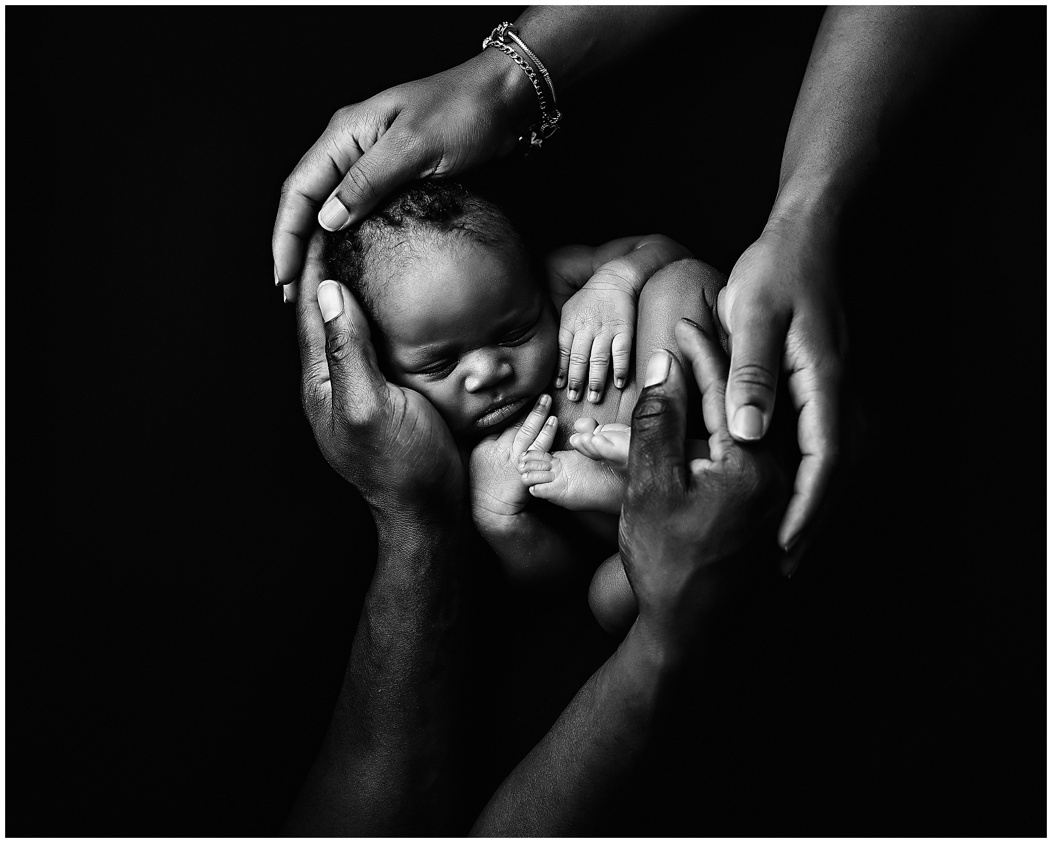 parents holding baby in arms black and white photo