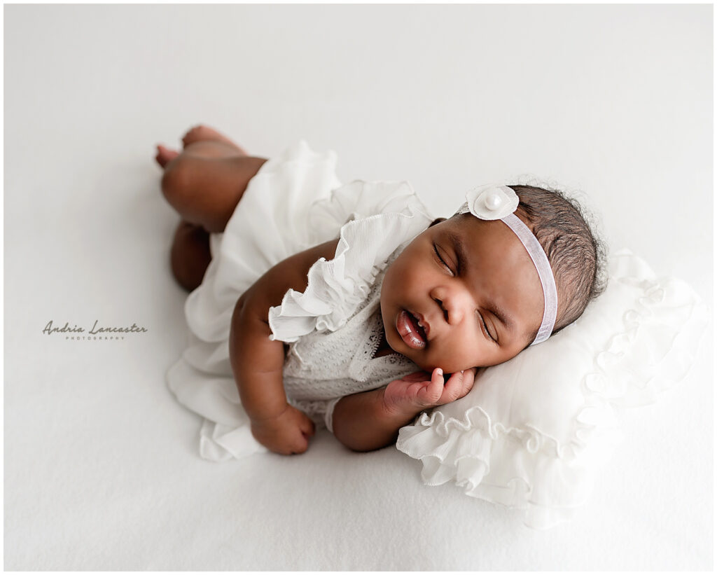 newborn baby girl with all white dress in side lay pose