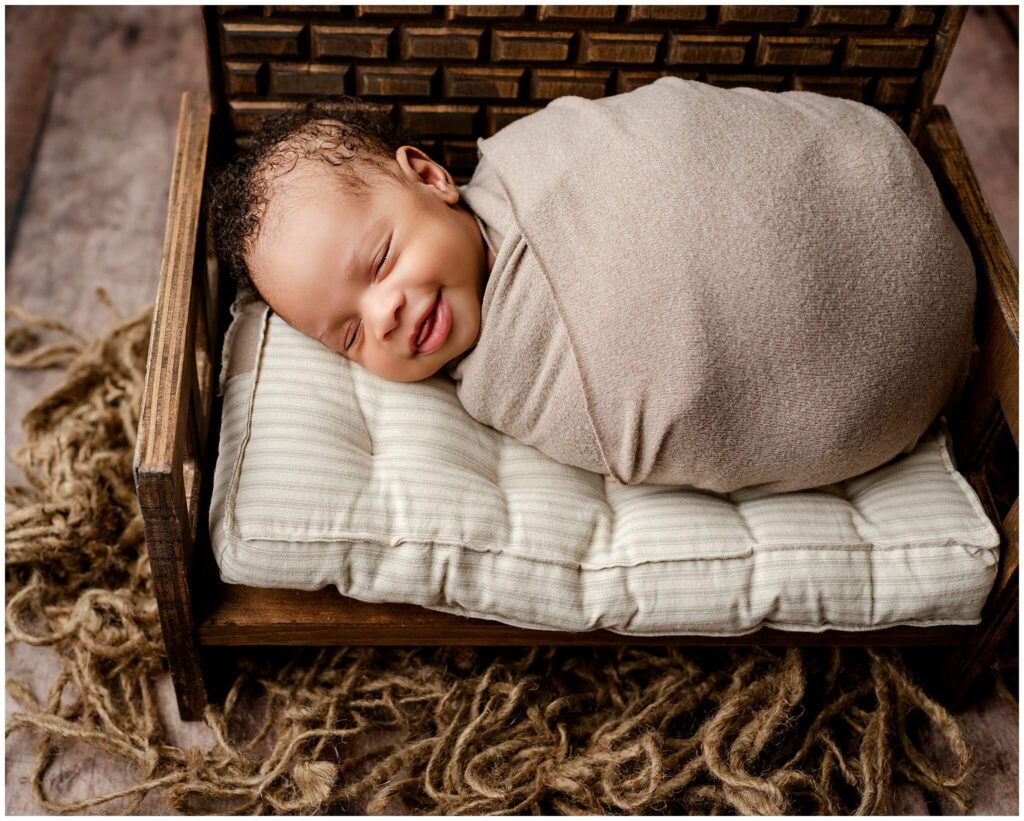 Newborn baby boy wrapped and sleeping soundly on a rustic wooden bench