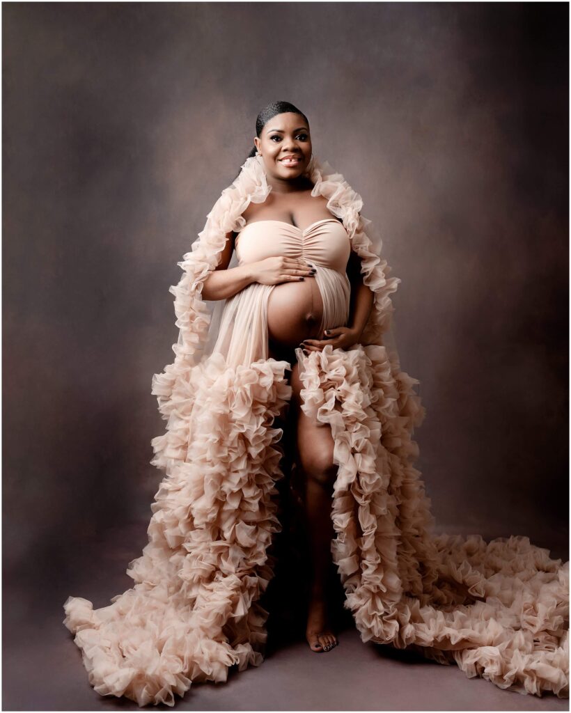 Expectant mother cradling her baby bump in a beautiful ruffled gown.