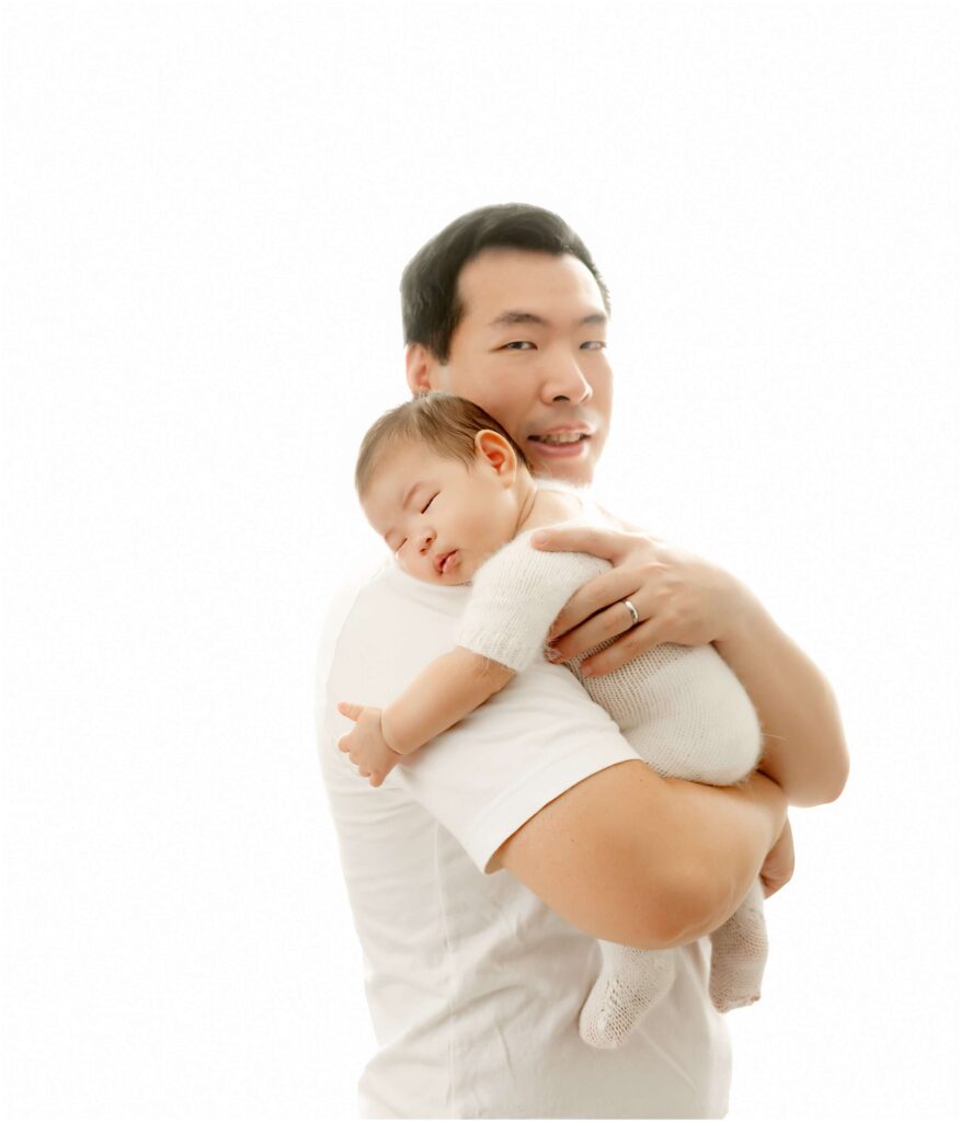 Father holding his newborn baby on his shoulder.